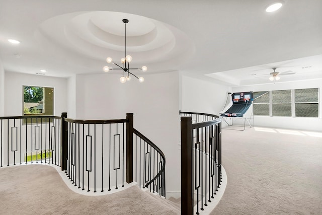 corridor with a notable chandelier, a raised ceiling, and carpet