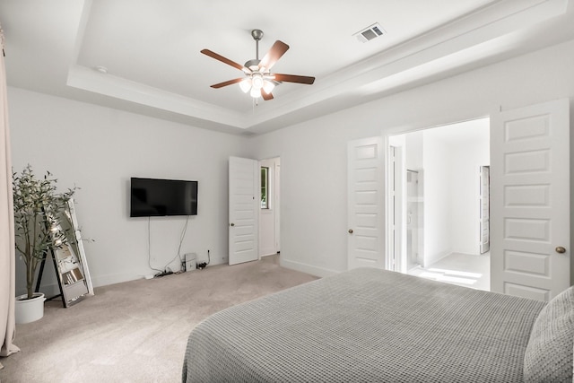 carpeted bedroom with a tray ceiling and ceiling fan