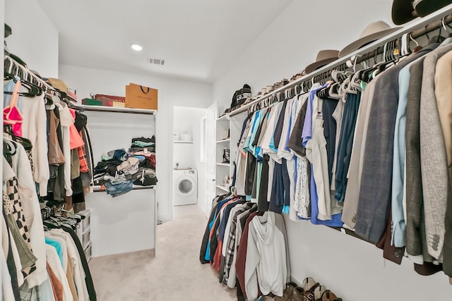 spacious closet featuring light colored carpet and washer / clothes dryer