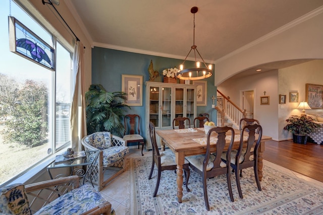2106 Springwood, Brenham, TX 77833 - dining room featuring a chandelier, arched walkways, ornamental molding, stairs, and light wood-style flooring
