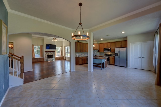 2106 Springwood, Brenham, TX 77833 - kitchen with appliances with stainless steel finishes, open floor plan, arched walkways, brown cabinetry, and tasteful backsplash