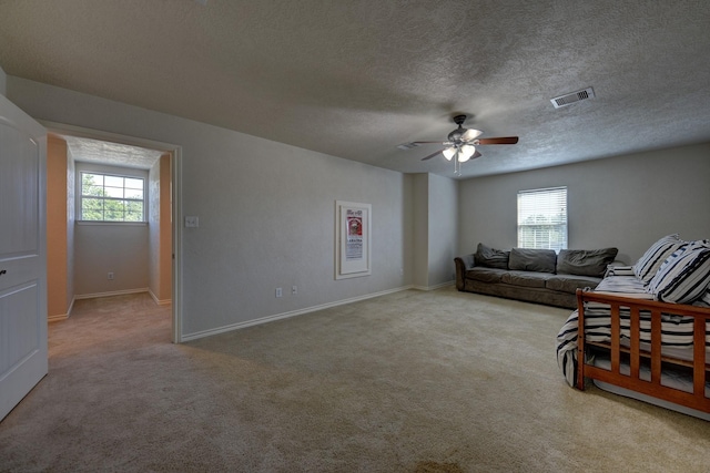 2106 Springwood, Brenham, TX 77833 - living area featuring a ceiling fan, healthy amount of natural light, carpet flooring, a textured ceiling, and baseboards