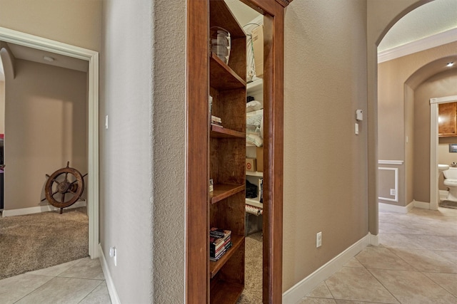 corridor with light tile patterned floors and crown molding