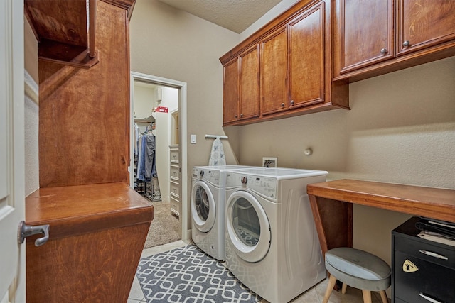 washroom featuring cabinets, washer and dryer, light tile patterned floors, and a textured ceiling