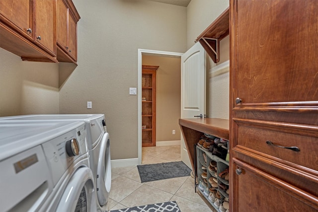 clothes washing area featuring cabinets, washer and dryer, and light tile patterned floors