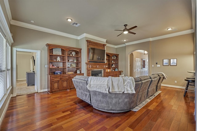 living room with crown molding, dark wood-type flooring, and ceiling fan