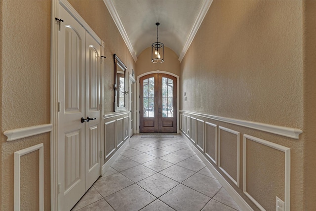 foyer featuring lofted ceiling, light tile patterned floors, ornamental molding, and french doors