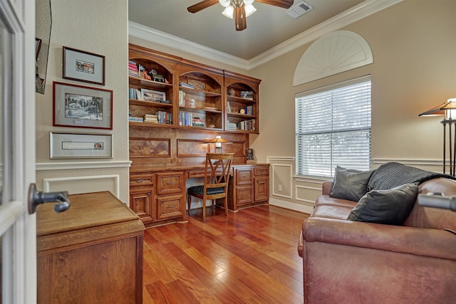 office space featuring built in desk, ornamental molding, light hardwood / wood-style floors, and ceiling fan