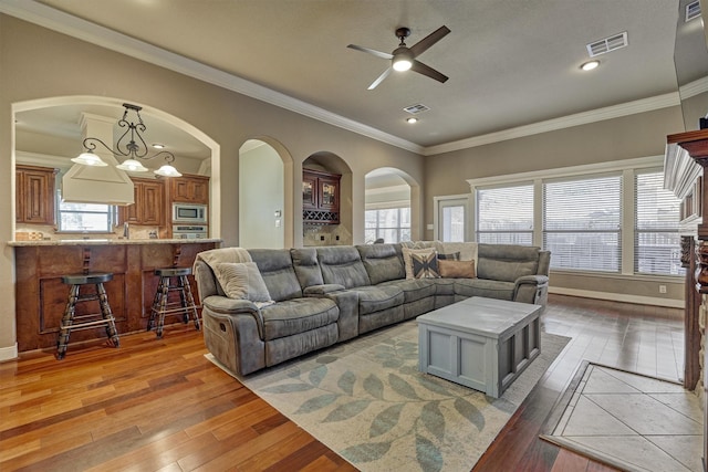 living room with crown molding, ceiling fan, a healthy amount of sunlight, and dark hardwood / wood-style floors