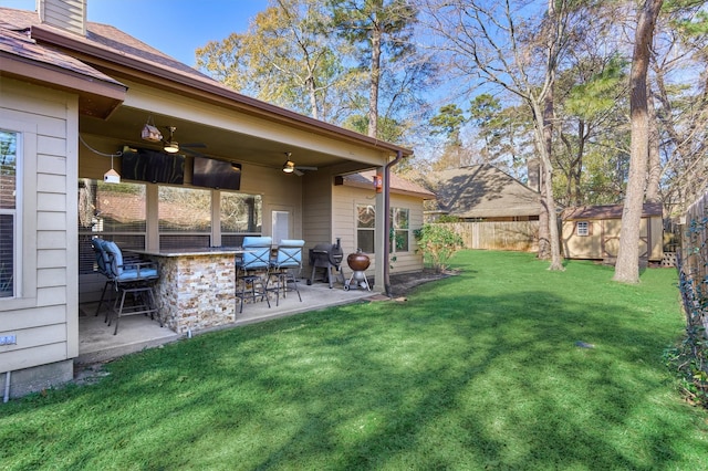 view of yard featuring ceiling fan, a storage shed, exterior bar, and a patio area