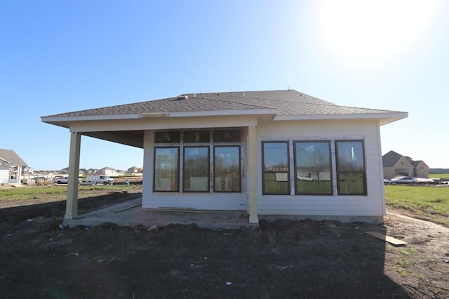 back of house with roof with shingles