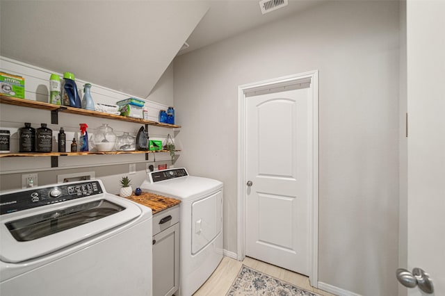 clothes washing area with washing machine and dryer and light wood-type flooring