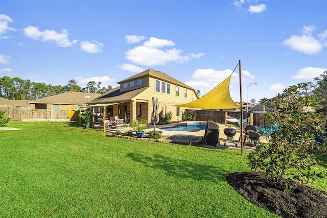 rear view of property with a yard, a fenced in pool, and a patio area