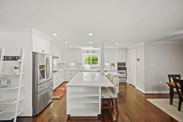 kitchen with stainless steel appliances, white cabinetry, a kitchen island, and tasteful backsplash