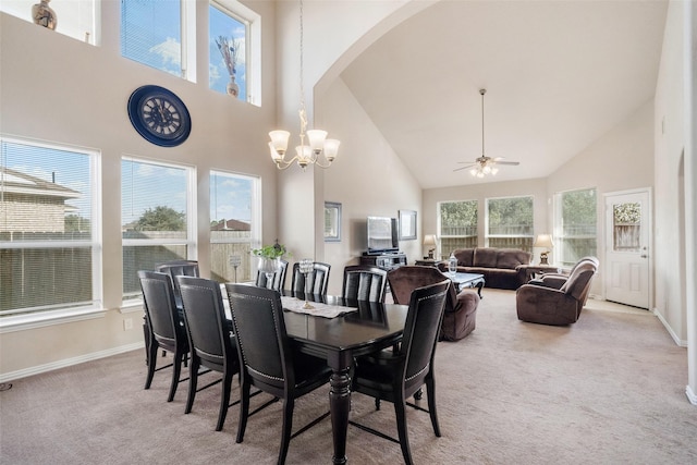 dining space with ceiling fan with notable chandelier, a towering ceiling, and light colored carpet