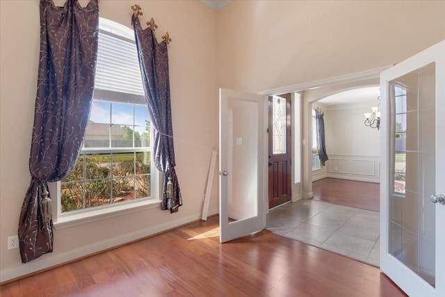 foyer featuring an inviting chandelier, a wealth of natural light, french doors, and wood-type flooring