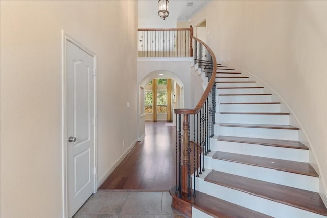 stairway with a towering ceiling and tile patterned floors