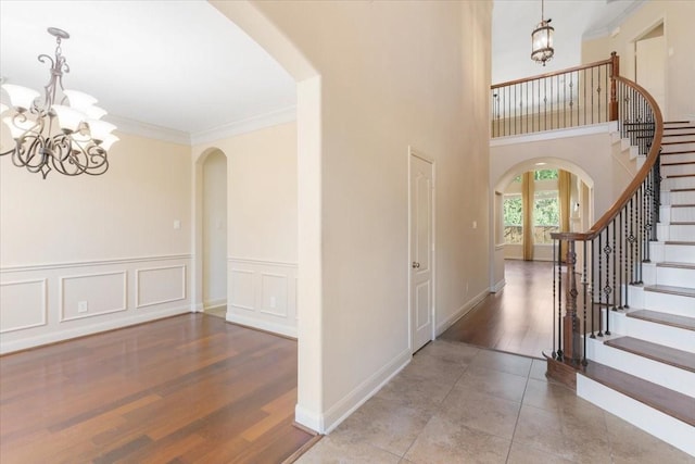 foyer entrance with crown molding, tile patterned floors, a chandelier, and a towering ceiling