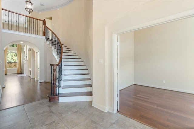 staircase with crown molding, a towering ceiling, and tile patterned floors