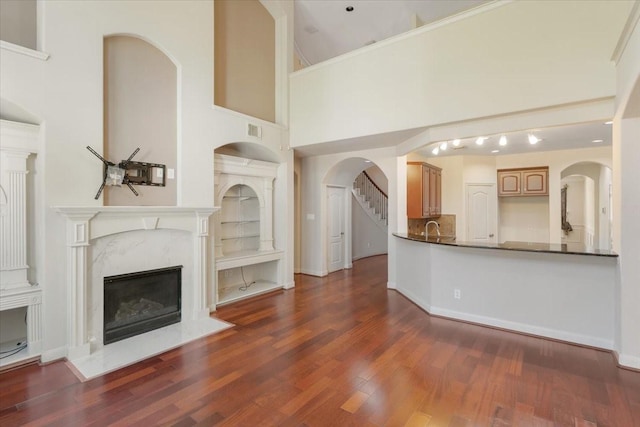 unfurnished living room with sink, a fireplace, dark hardwood / wood-style floors, and a high ceiling