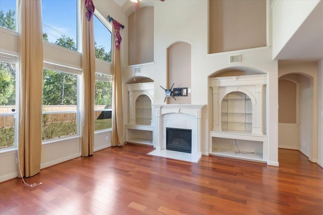 unfurnished living room with wood-type flooring and a high ceiling