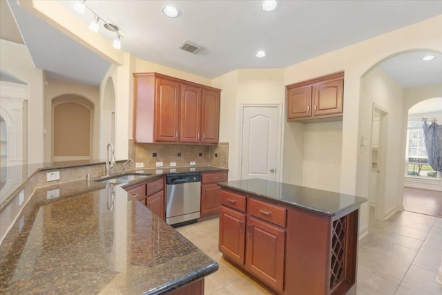 kitchen with sink, stainless steel dishwasher, a center island, and dark stone counters