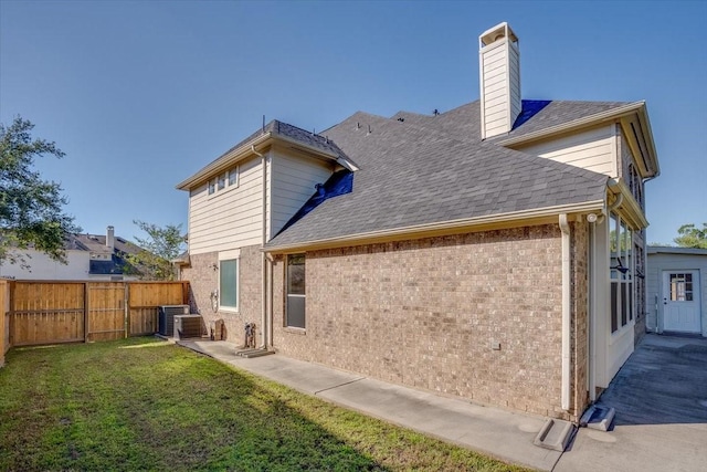 rear view of house with central AC and a lawn