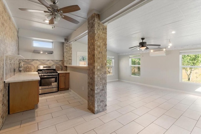 kitchen featuring ornate columns, stainless steel range with gas cooktop, a healthy amount of sunlight, and lofted ceiling