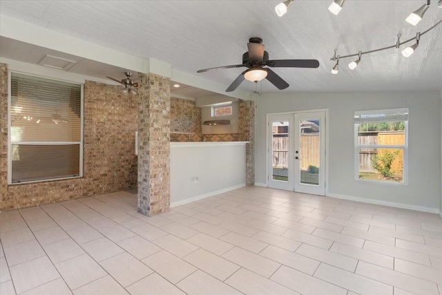 spare room with vaulted ceiling, brick wall, rail lighting, light tile patterned floors, and french doors