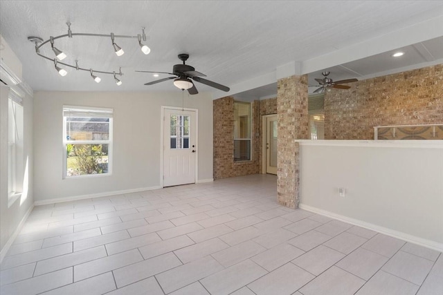 unfurnished living room featuring ceiling fan, brick wall, and light tile patterned floors