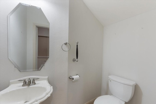 bathroom featuring sink, vaulted ceiling, and toilet