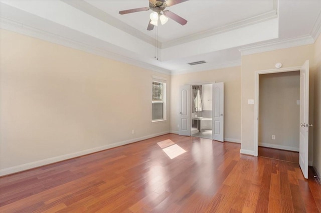 unfurnished bedroom featuring a raised ceiling, crown molding, wood-type flooring, and ceiling fan