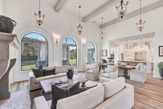 living room featuring a high ceiling, beam ceiling, an inviting chandelier, and light hardwood / wood-style flooring