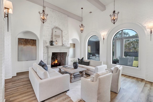 living room with beamed ceiling, wood-type flooring, a high ceiling, and a notable chandelier