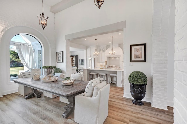 dining space featuring sink, a chandelier, breakfast area, light hardwood / wood-style floors, and a high ceiling