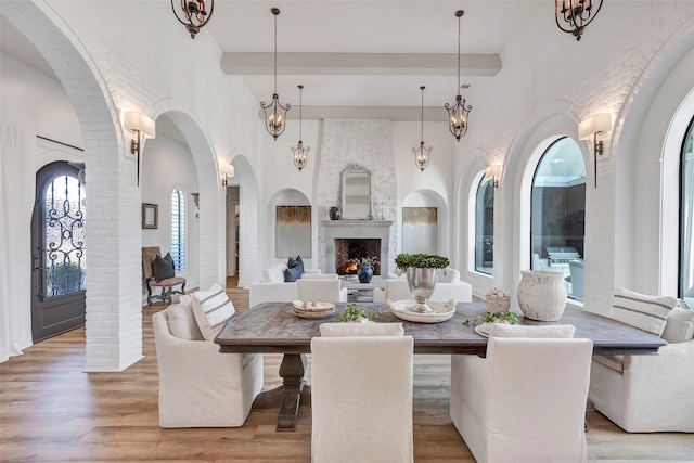 dining space featuring a towering ceiling, a large fireplace, and light hardwood / wood-style flooring