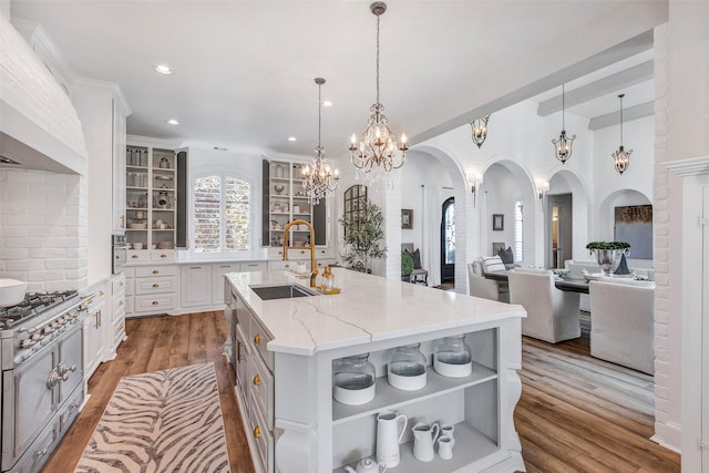 kitchen featuring pendant lighting, sink, custom exhaust hood, light stone counters, and a spacious island