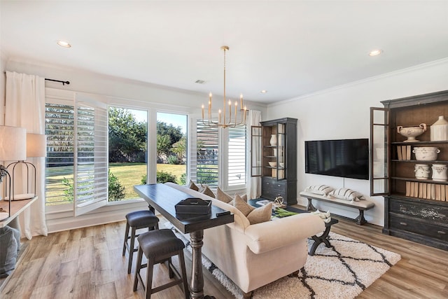 living room featuring a notable chandelier, ornamental molding, light hardwood / wood-style floors, and a healthy amount of sunlight