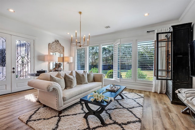 living room with crown molding, light hardwood / wood-style floors, french doors, and a chandelier