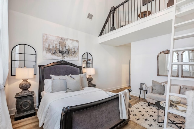 bedroom featuring a high ceiling and light hardwood / wood-style floors