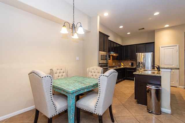 dining area featuring sink, light tile patterned floors, and an inviting chandelier