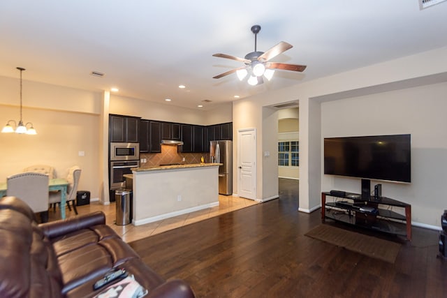 living room featuring ceiling fan with notable chandelier and light hardwood / wood-style floors