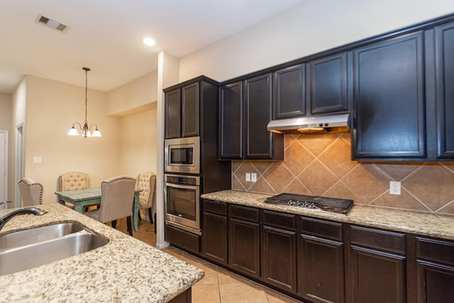 kitchen featuring appliances with stainless steel finishes, pendant lighting, tasteful backsplash, sink, and an inviting chandelier