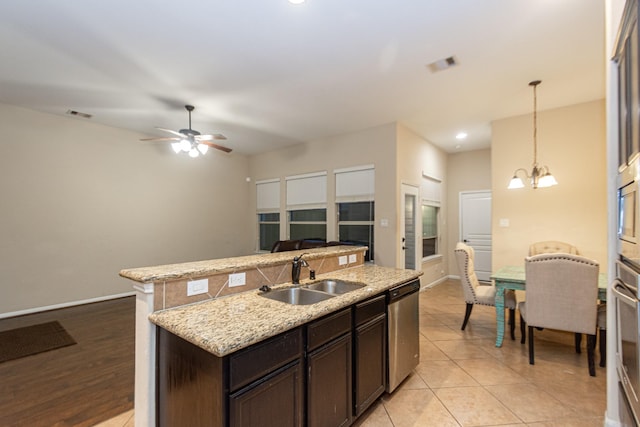 kitchen featuring decorative light fixtures, an island with sink, sink, stainless steel appliances, and dark brown cabinets