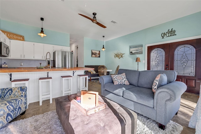 living room featuring french doors, ceiling fan, and sink