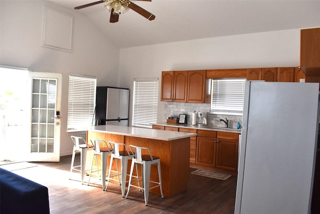 kitchen featuring a breakfast bar, lofted ceiling, stainless steel fridge, hardwood / wood-style flooring, and a center island