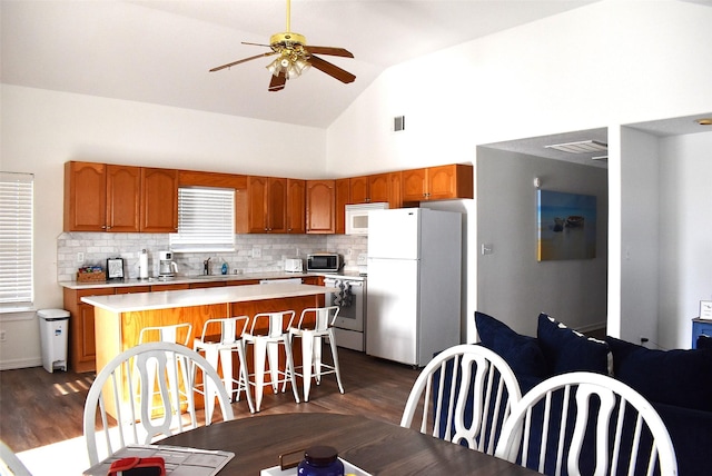 kitchen with sink, tasteful backsplash, ceiling fan, a kitchen island, and white appliances