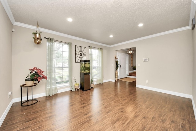 spare room with dark wood-type flooring, ornamental molding, and a textured ceiling