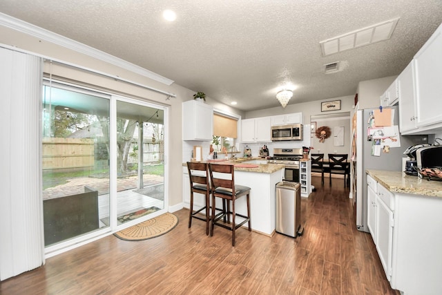 kitchen featuring stainless steel appliances, white cabinetry, a textured ceiling, and a kitchen breakfast bar