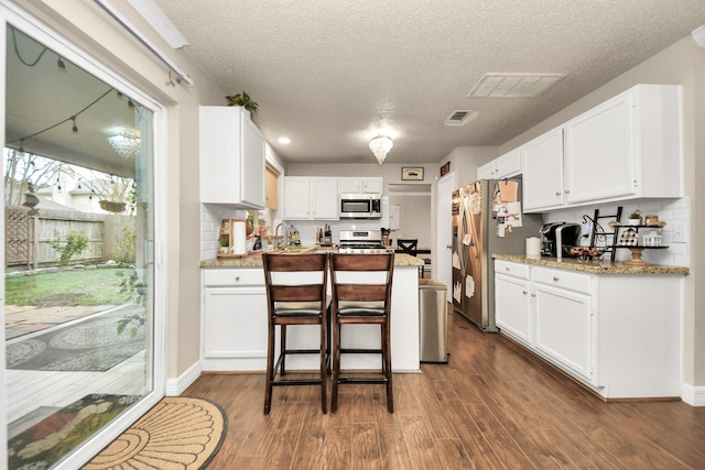 kitchen featuring dark hardwood / wood-style flooring, a textured ceiling, stainless steel appliances, and white cabinets